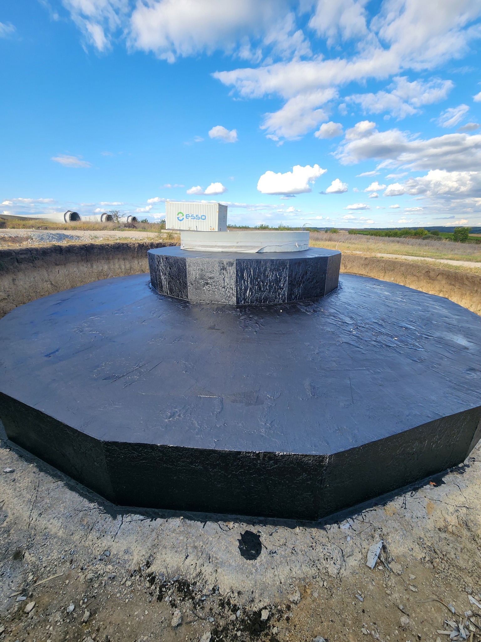 Fundația betonată a turbinei la Pojăreni, cu containerul ESSO în fundal